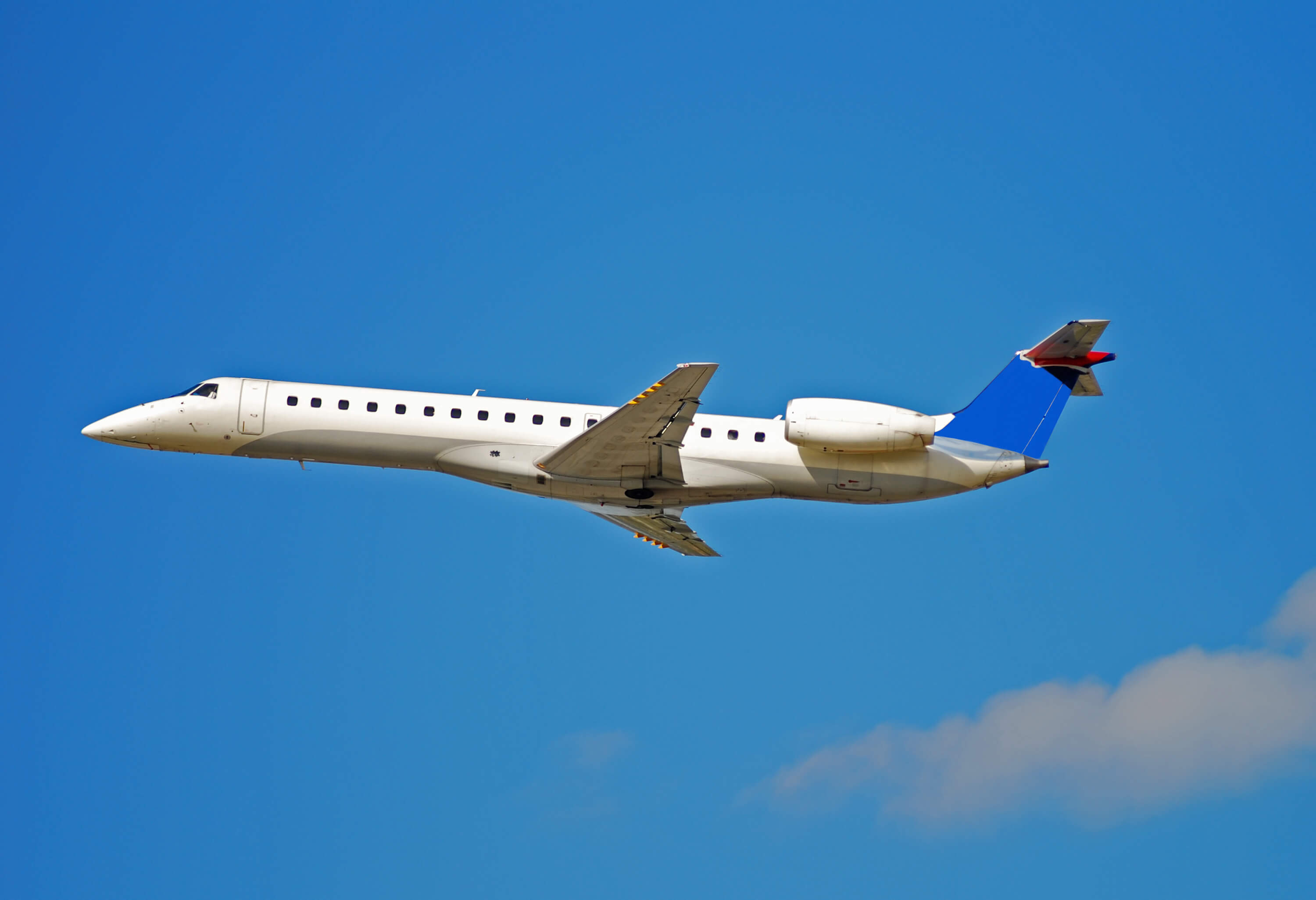 JSX Embraer ERJ jet flying in the air with blue clear sky behind it representing jets that fly from jsx