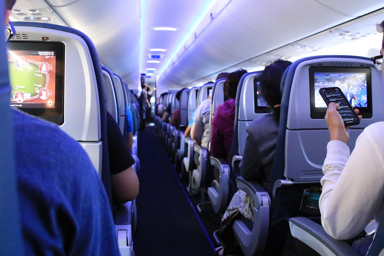 Passengers seated inside airplane cabin preparing for takeoff, representing travel to or from Oakland International Airport (OAK)